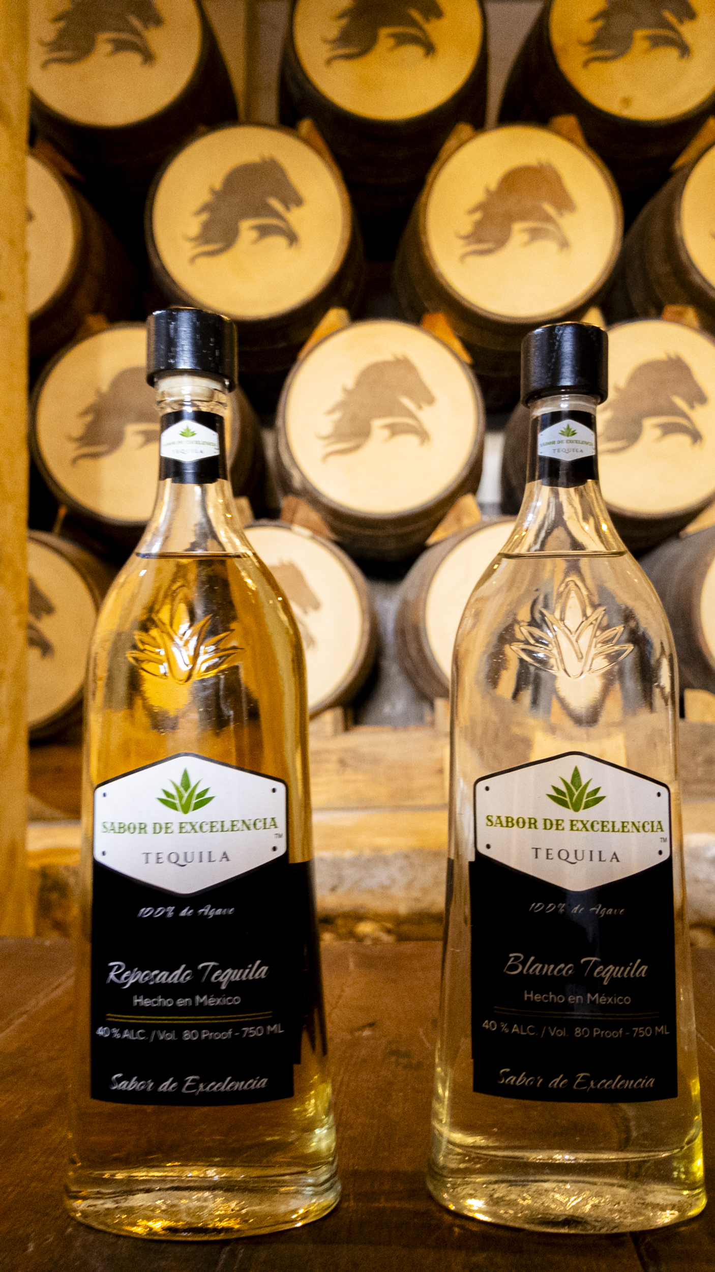 Sabor de Excelencia Reposado and Blanco in front of barrels